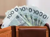 Portfel z banknotami 100 zł. Czy urlop wychowawczy jest płatny? To pytanie nurtuje wielu rodziców, a pieniądze w portfelu mogą pomóc w podjęciu decyzji.