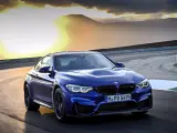 Niebieskie BMW M2 CS pędzi po torze wyścigowym podczas zachodu słońca.