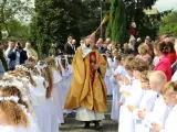 Uroczystość I Komunii Świętej. Dzieci w bieli, ksiądz błogosławi. Zastanawiasz się, ile kosztuje talerzyk na komunie?