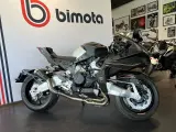 Czarny motocykl Bimota Tesi H2 z włókna węglowego, z podwójnym wydechem i sportowym zawieszeniem, gotowy do jazdy.