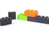Klocki z drukarki 3D, wykonane z materiału ABS, w kolorach czarnym, zielonym i pomarańczowym, ułożone na białym tle.