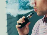 Hombre vapeando, exhala humo blanco. El vapear sube la tensión, cuidado con tu salud.