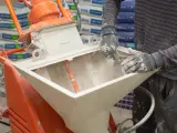 Pracownik zasypuje maszynę do tynków. Sprawdź tynki maszynowe cena za m2 z materiałem.