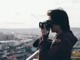 Młody mężczyzna z aparatem w rękach, uchwycony w kadrze z widokiem na miasto. Jego wzrok skupiony jest na obiektywie, jakby chciał uwiecznić piękno chwili za pomocą viewnx 2.