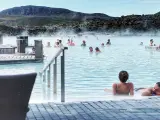 Relaks w Blue Lagoon, geotermalnym basenie z parą unoszącą się nad turkusową wodą. Ludzie kąpią się i odpoczywają.