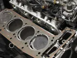 Nowa uszczelka pod głowicą czeka na montaż. Widać cylindry silnika i fragmenty bloku.