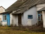 Stary dom z niebieskimi drzwiami i oknami, zarośnięty chwastami. Budowa domu w granicy działki wymaga zgody sąsiada.