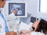 Lekarka pokazuje na ekranie USG obraz dziecka, które ma 22 tydzień ciąży. Kobieta leży na łóżku, uśmiecha się.