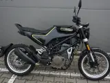 Czarny motocykl Husqvarna Svartpilen 401 z żółtymi akcentami, gotowy na miejskie przygody.