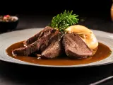 Zartes Tafelspitz-Rezept auf einem Teller mit Sauce, Beilage und Rosmarinzweig.
