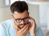 Mężczyzna w okularach z bólem zęba, szuka sposobu na ból zęba z dziurą.