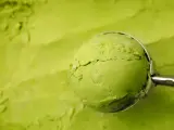 Eine Kugel cremiges Matcha-Eis wird mit einem Löffel aus einer Schüssel gehoben. Perfekt für ein erfrischendes Matcha Eis Rezept.