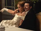 Elegancka para przy stole, zapowiedź nowych produkcji Netflix. Kobieta w białej sukni z rękawiczkami, mężczyzna w czarnym fraku.