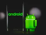 Zielony robot Android obok telefonu z logo Android 13.
