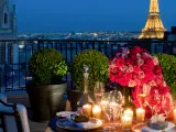 Cena romántica en París para San Valentín. Mesa con rosas, velas y Torre Eiffel iluminada al fondo.