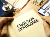 Książka z napisem "CROUZON SYNDROME", stetoskop, dokument "MEDICAL HISTO" i lekarstwa.
