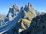 Majestätische Felszinnen ragen in den blauen Himmel. Eine **Seceda Wanderung** führt durch grüne Almwiesen und felsiges Gelände.