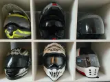 Sześć kasków motocyklowych w różnych kolorach i stylach, ułożonych w sześciu przegrodach.