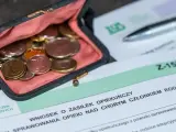Portmonetka z monetami leży obok formularza ZUS Z-15B, który dotyczy wniosku o zasiłek opiekuńczy.