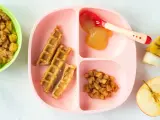 Baby-freundliche Apfelwaffeln mit Apfelmus und Zimt-Apfelstückchen auf einem rosa Teller. Ein halber Apfel und eine Banane liegen daneben.