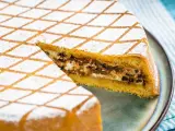 Una fetta di cassata al forno, con la sua copertura a rombi di zucchero a velo, rivela un ripieno goloso di ricotta e cioccolato.