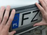 Dwie dłonie trzymają polską tablicę rejestracyjną z literami FZ.