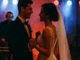 Para młoda tańczy przy dźwiękach wzruszających piosenek na wesele. W tle DJ w słuchawkach.