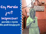 Uśmiechnięta kobieta z tatuażem henny na ręce pozuje na tle uliczki w Maroku. Tekst pyta: "Czy Maroko jest bezpieczne?".