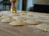 Świeże ravioli na drewnianej desce, posypane mąką. Zastanawiasz się, ravioli z czym podawać?