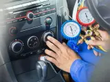 Mechanik sprawdza ile czynnika do klimatyzacji pozostało w samochodzie, używając manometrów.