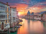 Tramonto sul Canal Grande, un quadro perfetto di posti romantici a Venezia. Palazzi storici e la Basilica di Santa Maria della Salute riflettono i colori del cielo.