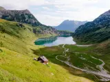 Idyllischer Salzburg See, umgeben von grünen Bergen. Eine Hütte am Hang lädt zum Verweilen ein.