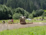 Bambini giocano vicino a un galeone di legno in un lago, mentre altri si rilassano sull'erba. Perfetto per le **san vigilio di marebbe passeggiate** estive.