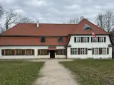 Dworek z czerwonym dachem i białymi ścianami, z polską flagą. Słychać tu echo gwary pomorskiej.