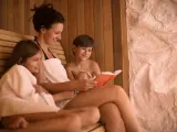 Kobieta czyta książkę dzieciom w saunie.
