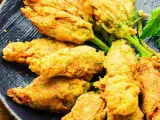 Fiori di zucca ripieni dorati e croccanti, serviti su un piatto blu scuro.