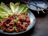 En tallrik med krispiga, glaserade kycklingvingar, toppade med hackade jordnötter och salladslök. Serveras med krispiga salladsblad. En utsökt koreansk matupplevelse.