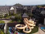 Karpacz hotel z aquaparkiem oferuje zjeżdżalnie i baseny. Widać też góry w tle.