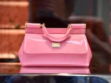 Różowa, lakierowana torebka od Dolce & Gabbana, symbol luksusowych marek torebek, błyszczy na tle sklepu.