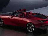 Czerwony kabriolet Rolls-Royce, najdroższe auto na świecie, lśni przy wodzie.