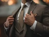 Uomo in abbigliamento business formal marrone, con camicia bianca e cravatta a trama.