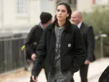 Donna con giacca Carhartt nera e cardigan grigio, cuffiette bianche, cammina con sicurezza.