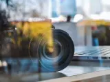 Winieta fotografia: obiektyw Canon na tle laptopa, odbicia tworzą artystyczny efekt.