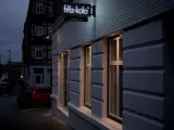 Neon-Schild "fritz-kola" über dem Eingang "dritter ort kiel". Ein rotes Auto parkt auf der Straße.