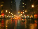 Luci sfocate di una strada cittadina di notte, con riflessi sull'asfalto bagnato, che ricordano l'effetto dell'astigmatismo.