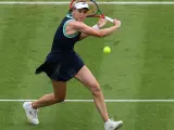 Jelena Rybakina w akcji, uderza piłkę na zielonym korcie.