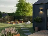 En modern trädgård med odlingslådor och en stenlagd gång leder till framsida hus entre.