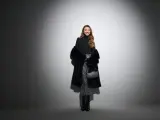 Uśmiechnięta kobieta w błyszczącej spódnicy i futrzanym płaszczu. Czy do filharmonii trzeba ubrać się elegancko? Ta stylizacja sugeruje, że tak!