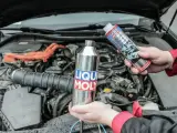Dwie ręce trzymają produkty Liqui Moly, jeden metalowy, drugi w sprayu, gotowe do czyszczenia katalizatora w silniku samochodu.