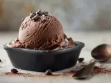 Ein Löffel Simons Eis, schokoladig und cremig, wartet neben Kakaopulver und Schokostückchen auf den Genuss.